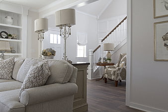 Bright white living room interior with beige sofa and staircase
