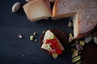 Artisanal Cheese Wedges with Pistachios and Jam on Slate