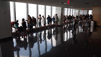 Tourists looking out window at One World Trade Center observation deck