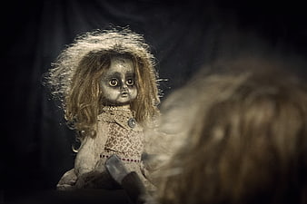 Creepy vintage doll with reflection in dark mirror