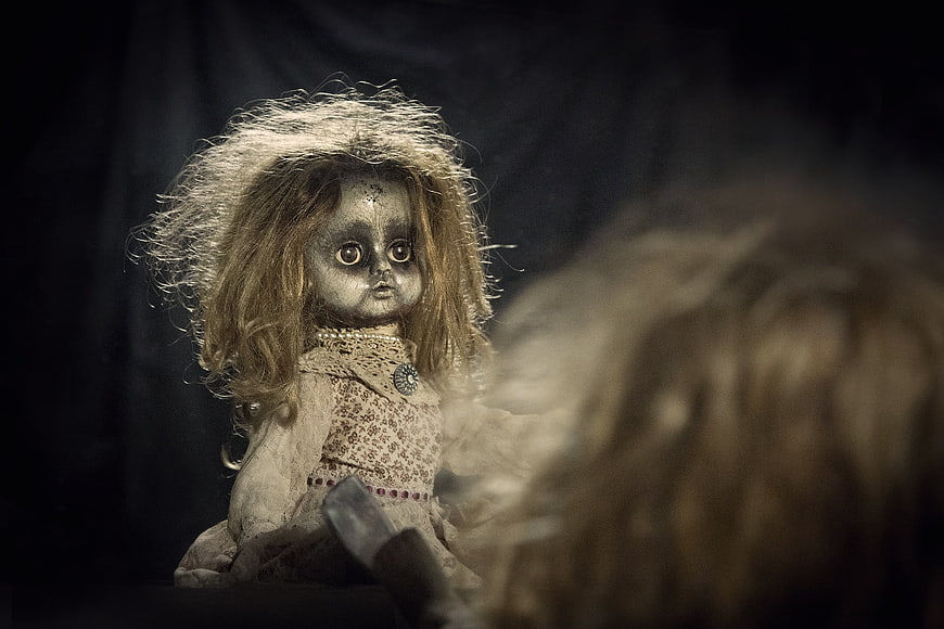 Creepy vintage doll with reflection in dark mirror
