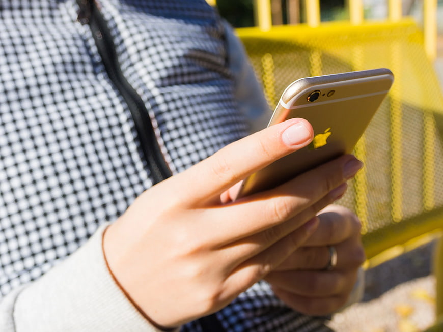Close-up of hands holding gold smartphone outdoors