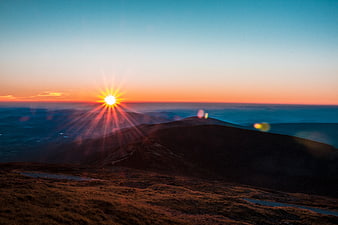 Sunset over mountain ridge with sunburst and lens flare
