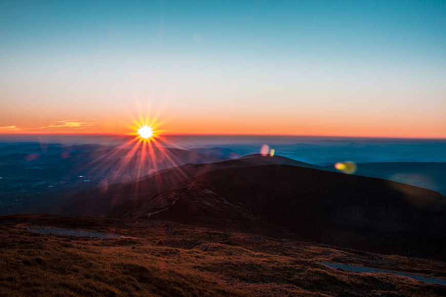 Sunset over mountain ridge with sunburst and lens flare