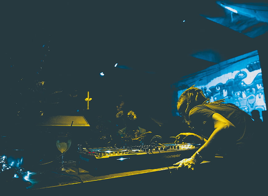 DJ Mixing Music in Dark Club with Neon Lights