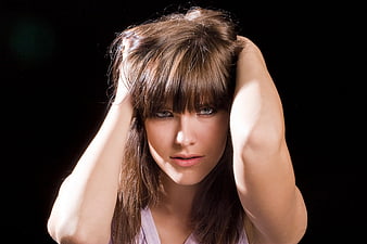 Dramatic portrait of woman with hands in hair against black background