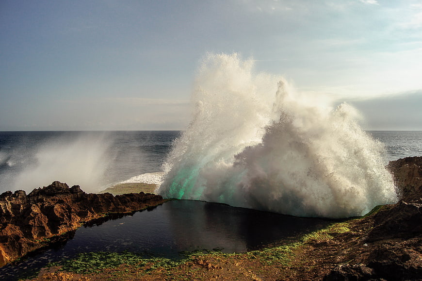 Powerful ocean wave crashing into rocky coastal pool