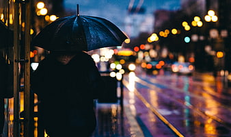 Silhouette of Person with Umbrella on Rainy City Street at Night