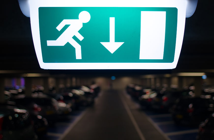 Illuminated Green Emergency Exit Sign in Parking Garage