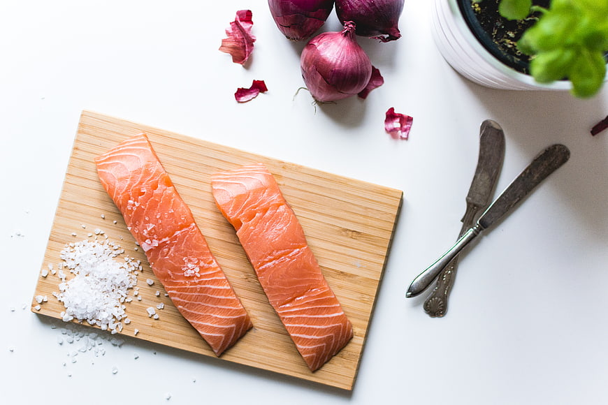 Fresh Salmon Fillets on Wooden Board with Salt and Onions