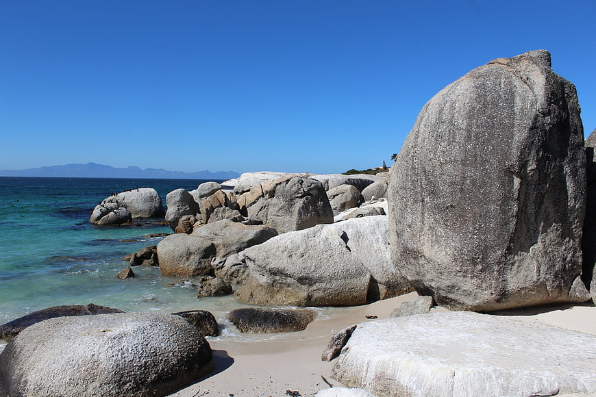 Sunny rocky beach with turquoise water and large boulders