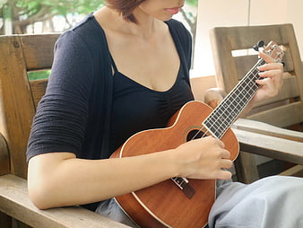 Woman Playing Ukulele on Wooden Chair