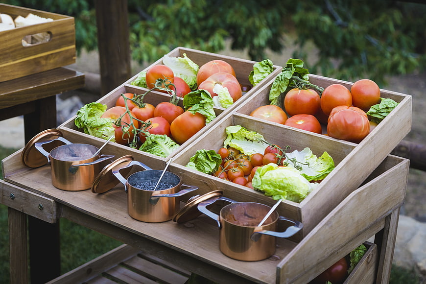 Fresh tomatoes and lettuce in wooden crates with copper pots