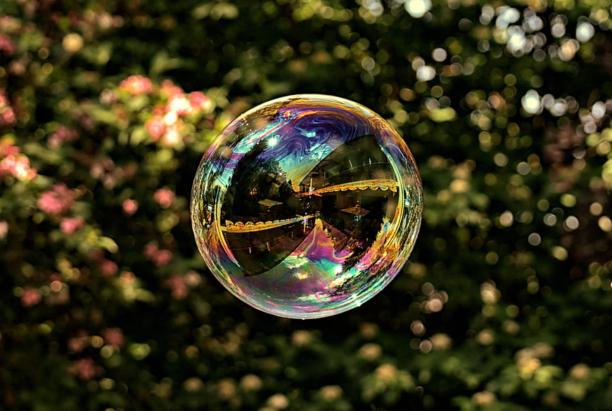 Iridescent Soap Bubble Floating Against Blurred Green Garden Background