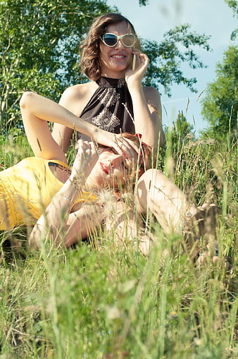 Two happy women relaxing in tall grass on a sunny summer day