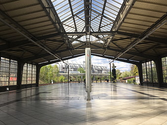 Empty modern train station platform with glass roof and tracks