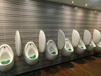 Modern white urinals in a row on a tiled wall