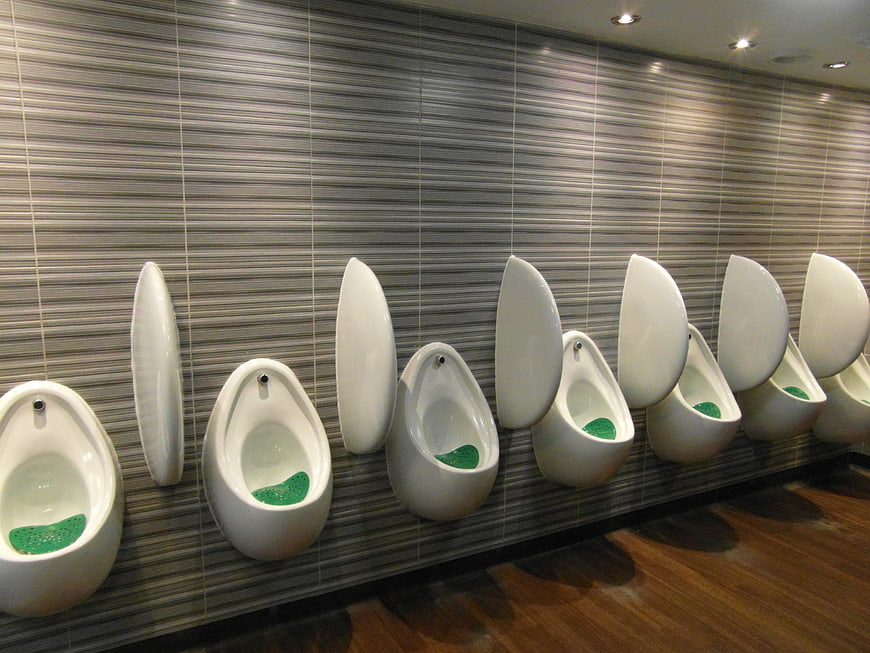 Modern white urinals in a row on a tiled wall