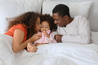 African American family cuddling in bed together
