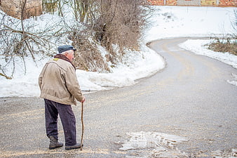 Senior man with walking stick on snowy winter road
