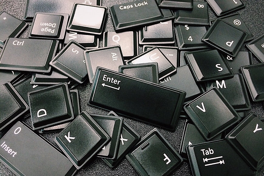 Scattered Black Computer Keyboard Keys on Dark Surface