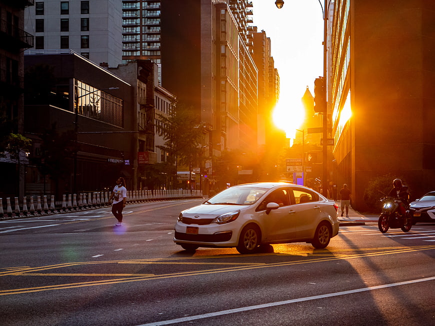 White Car Driving on City Street at Golden Hour Sunset