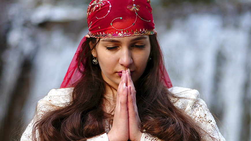 Woman in red headscarf praying with hands clasped