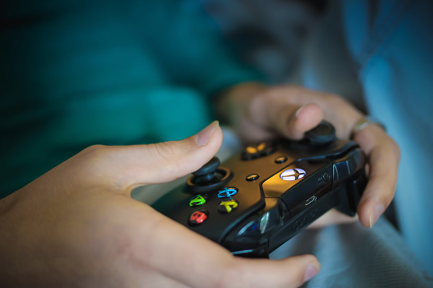 Close-up of hands holding a black Xbox One controller