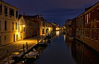 Venetian canal at night with boats and reflections