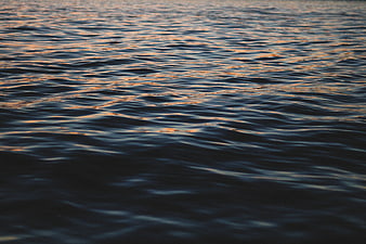 Calm ocean water ripples with sunset reflections