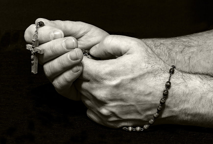 Close-up of hands holding a rosary in prayer