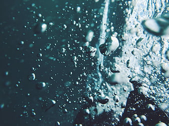 Close-up of rising air bubbles in dark blue water