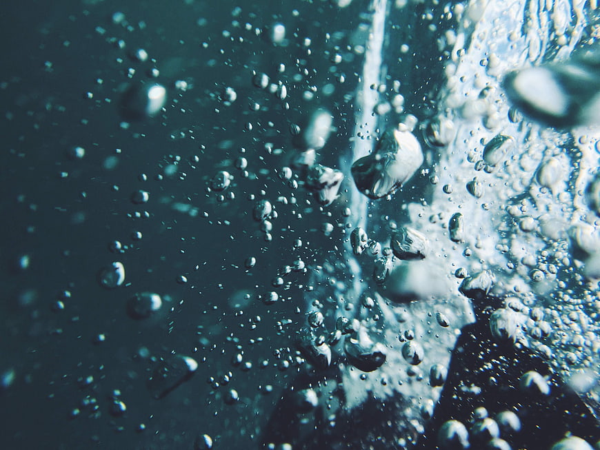 Close-up of rising air bubbles in dark blue water