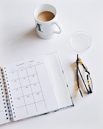 Minimalist workspace with coffee, planner, and glasses