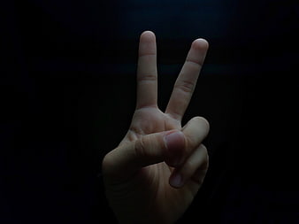 Hand Making Peace Sign Against Dark Background