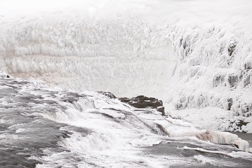 Frozen waterfall cascading over ice-covered cliffs in winter