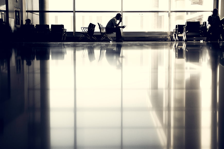 Silhouette of man waiting in airport terminal with floor reflection