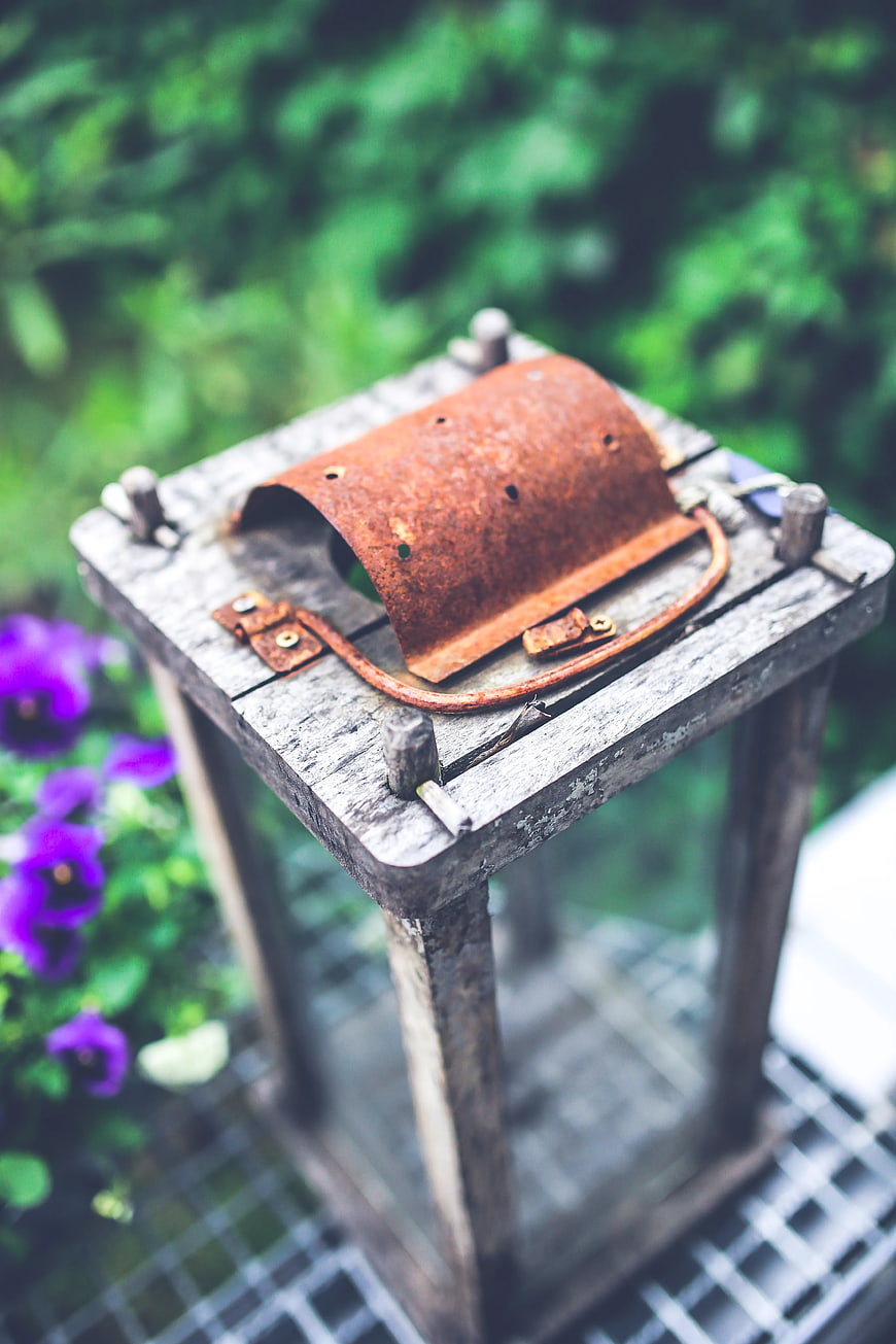 Rusty vintage lantern on wooden stand in garden