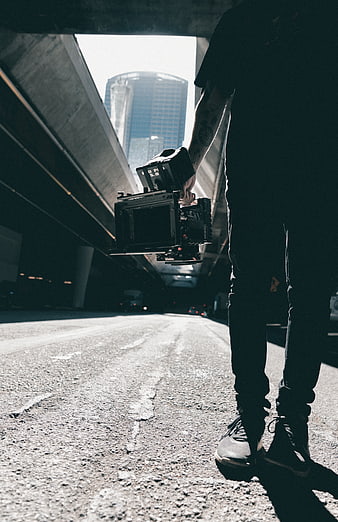 Cinematographer holding professional camera under urban overpass
