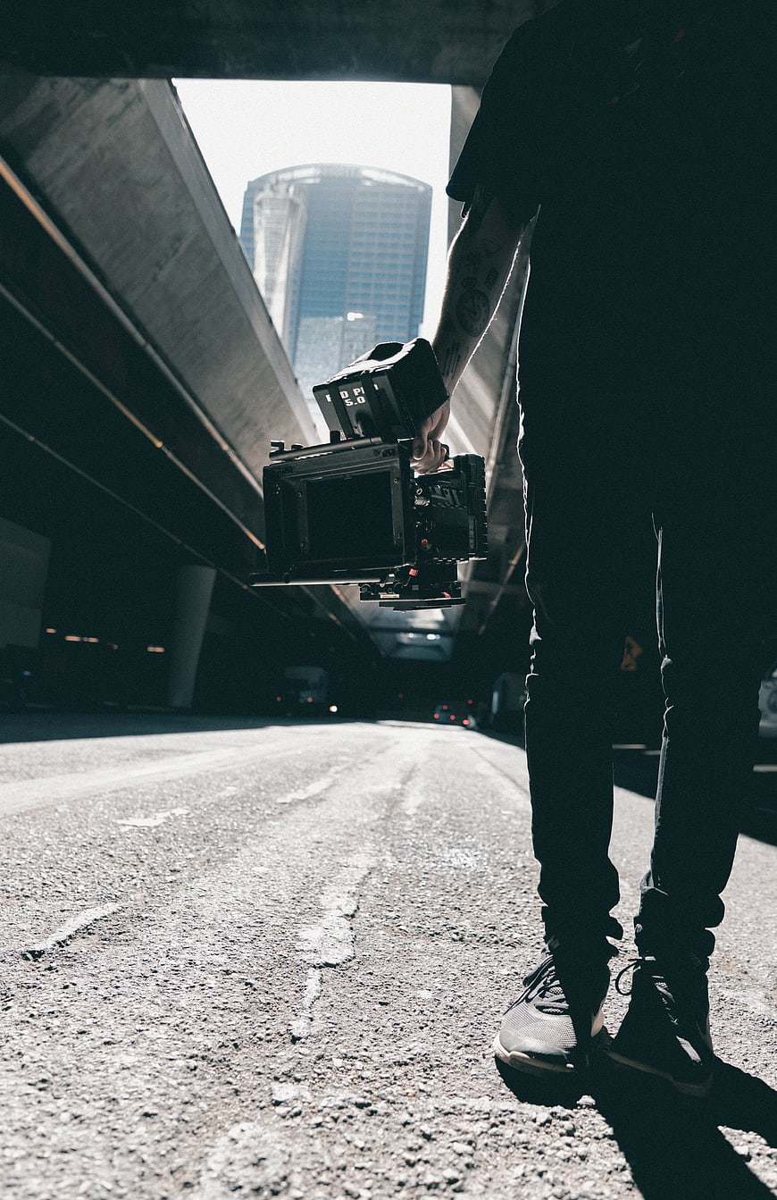 Cinematographer holding professional camera under urban overpass