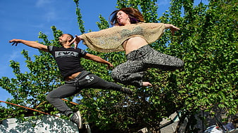 Dynamic Couple Jumping in Nature with Blue Sky Background