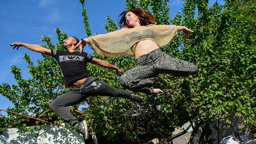 Dynamic Couple Jumping in Nature with Blue Sky Background