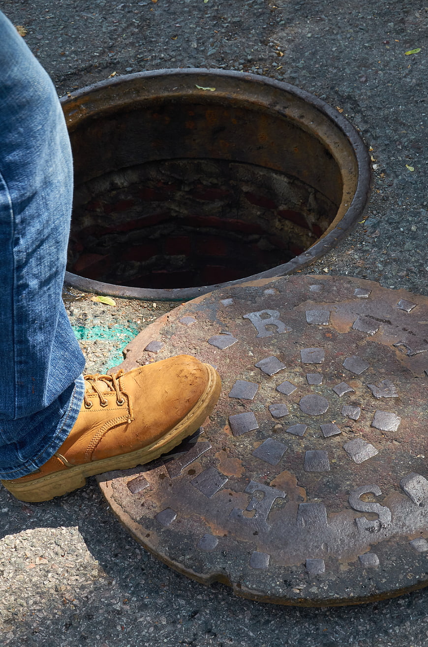 Worker's Boot on Open Manhole Cover