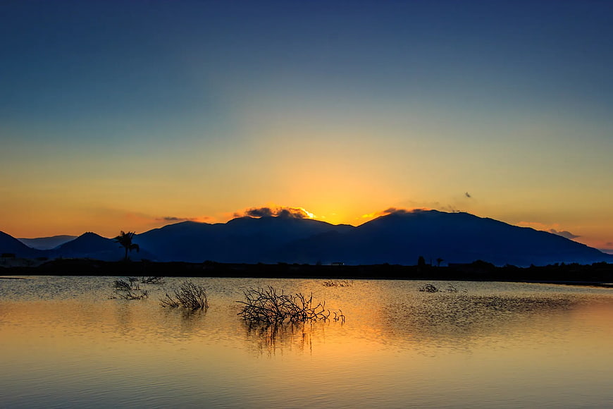 Serene Mountain Silhouette at Sunset Over Calm Lake