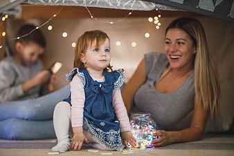 Happy family playing with fairy lights in a cozy indoor tent