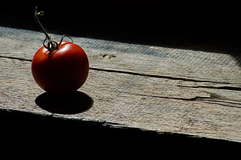 Single Red Tomato on Weathered Wooden Surface