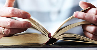Hands Opening An Old Book With Red Bookmark