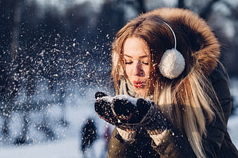 Woman Blowing Snow from Gloved Hands in Winter Park