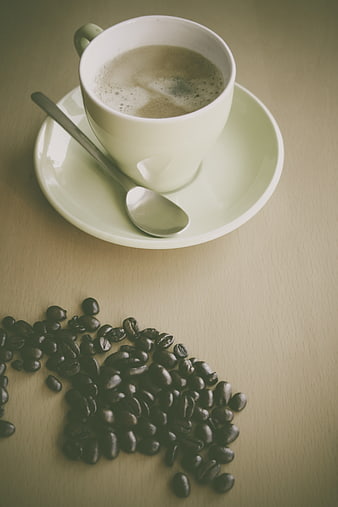 White coffee cup with beans on wooden table