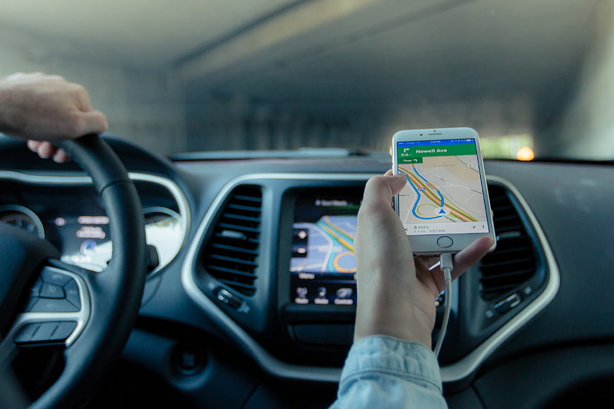 Driver using smartphone GPS navigation app while driving car